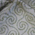 Spiral leaves with little blue buds on cream